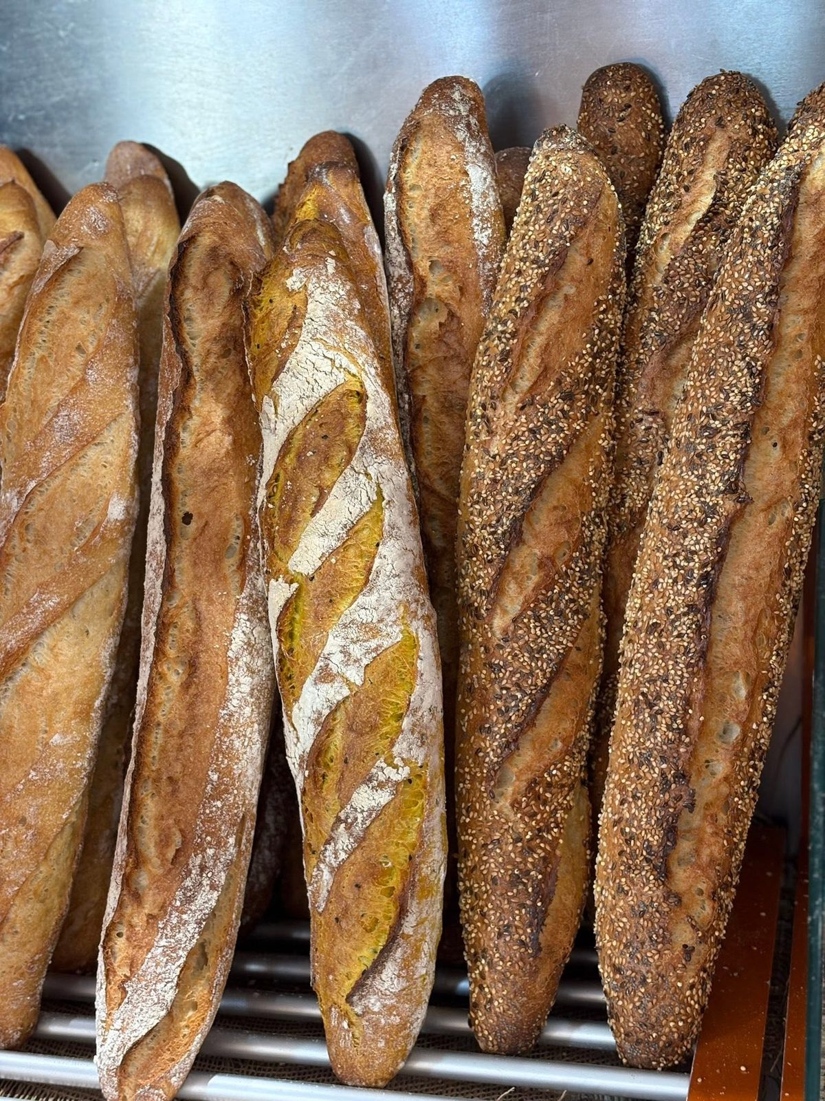 Baguettes tradition et pains de Tart'in alignés à la sortie du four